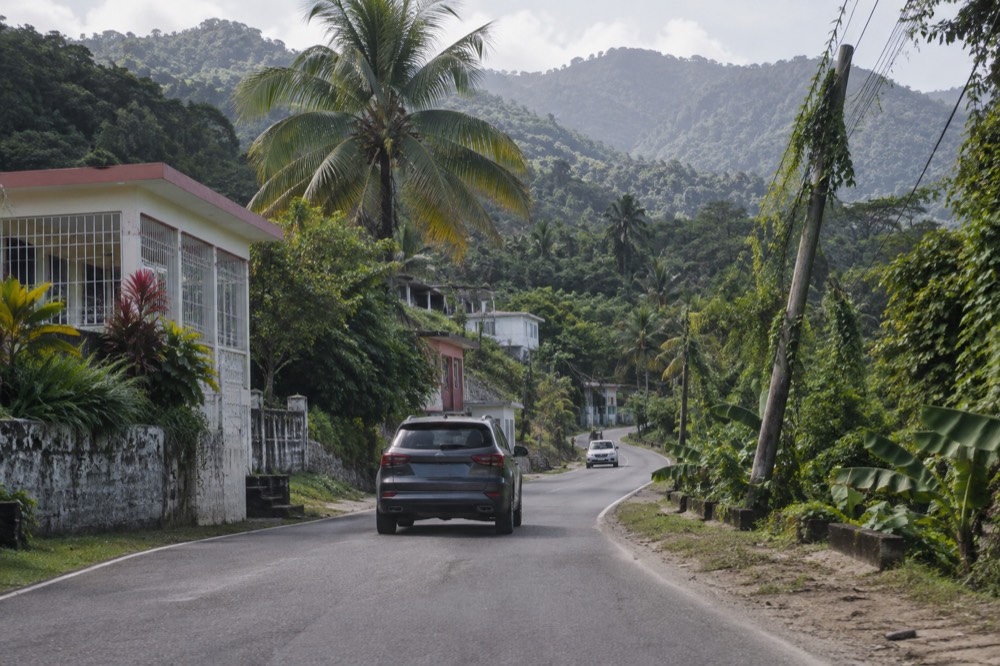 A winding mountain road climbing through layered green rainforest vegetation