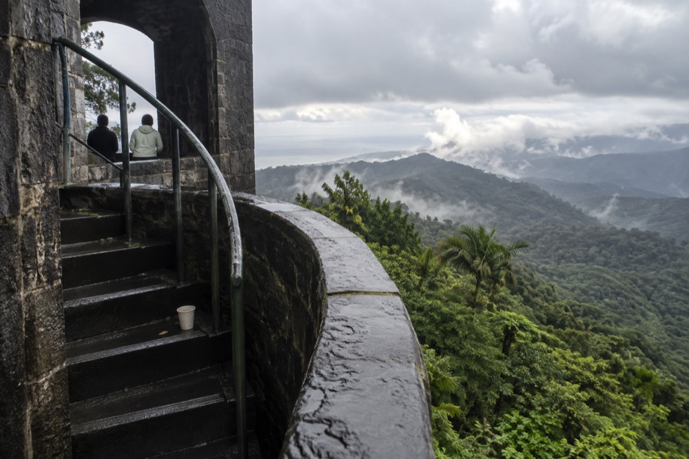 A stone observation tower overlooking layered green rainforest ridges