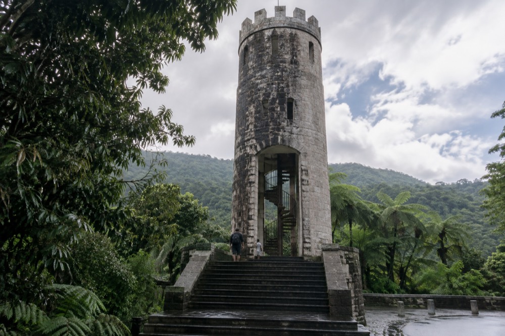 A stone observation tower rising above the rainforest canopy on a green mountainside