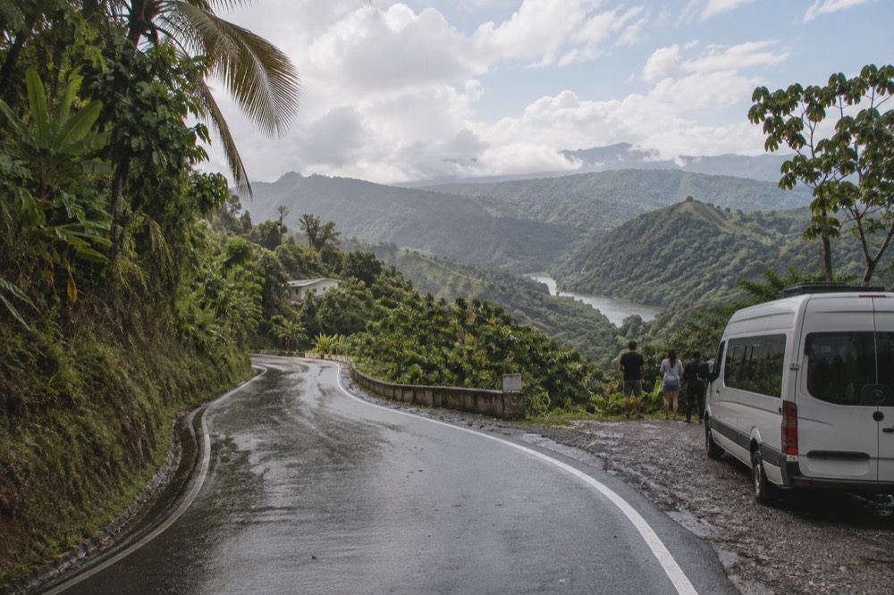 A winding mountain road climbing through layered green rainforest ridges