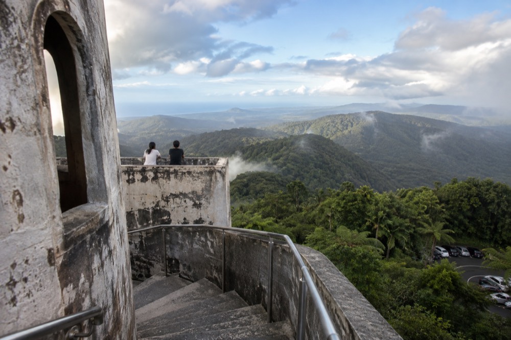 Stone observation tower overlooking green rainforest slopes toward the coast