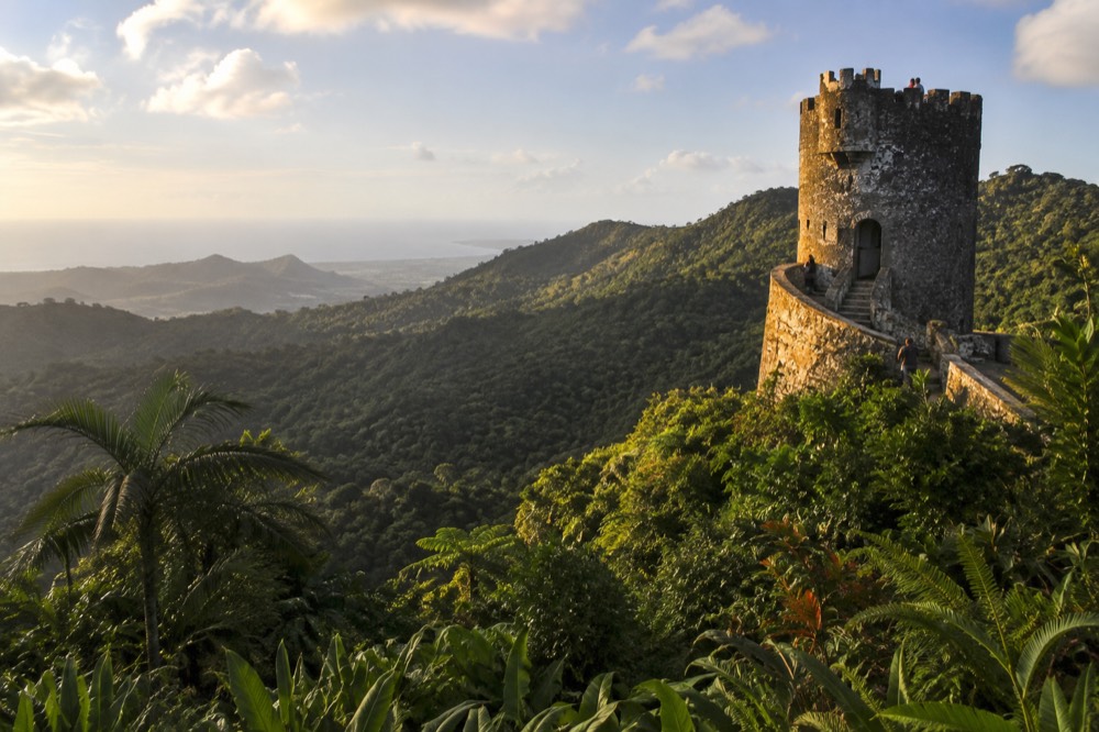 Stone observation tower rising above layered green forest ridges