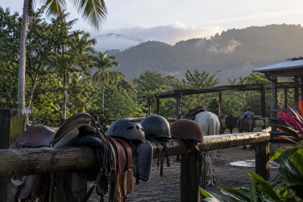 Rider gear and helmets laid out on a wooden rail before a private trail ride