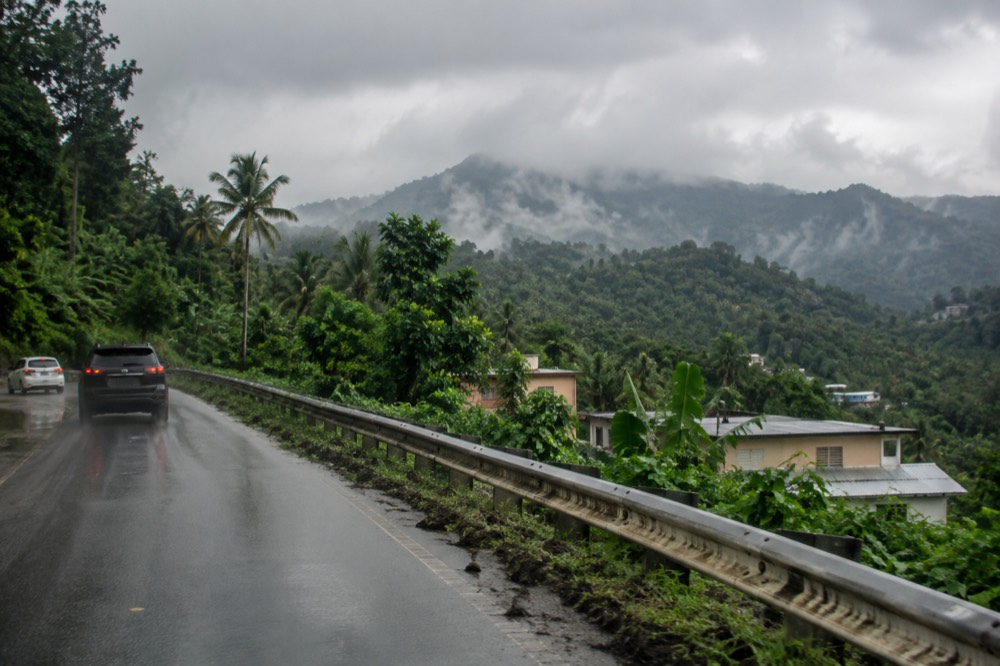 El Yunque forested ridge line rising behind a roadway with low clouds