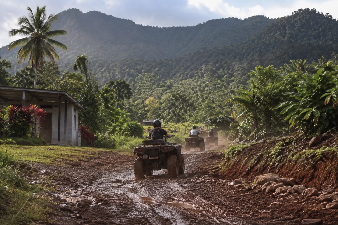 Mountainous rainforest canopy behind a private adventure park trail with muddy ATV tire tracks