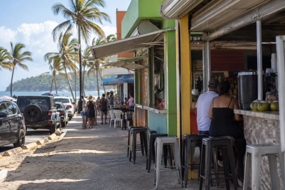 A row of colorful food kiosk storefronts along a beachside street