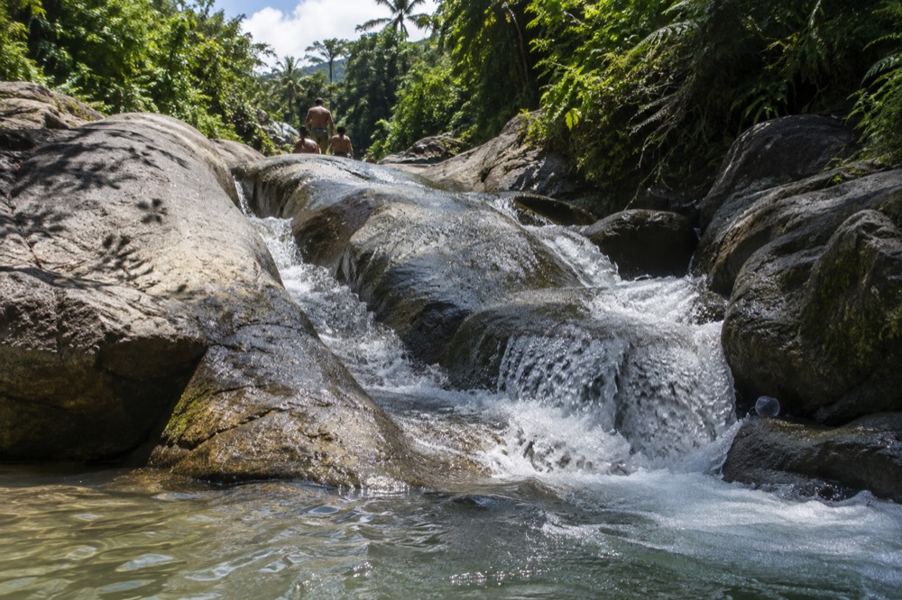 A natural rock water slide over smooth boulders with a small pool below