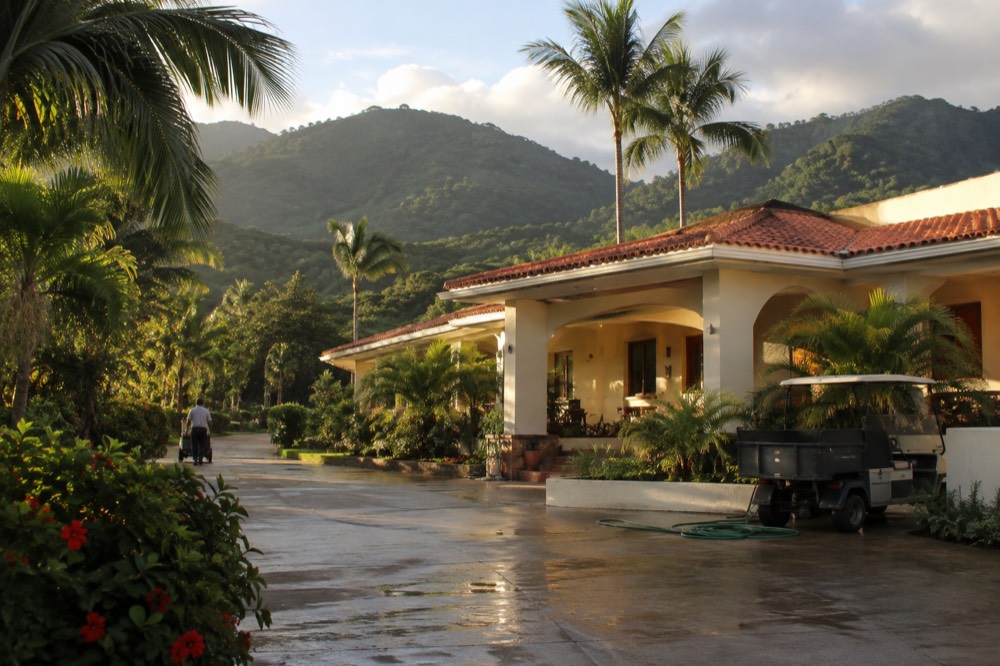 A resort building set against green mountain foothills near the coast