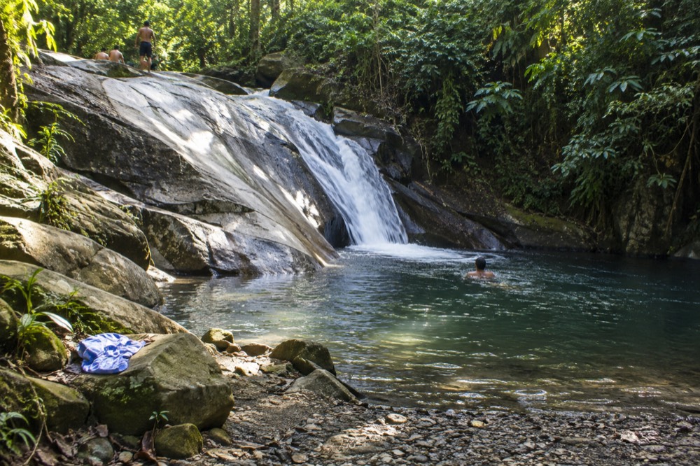 Natural rock waterslide with water flowing into a clear pool