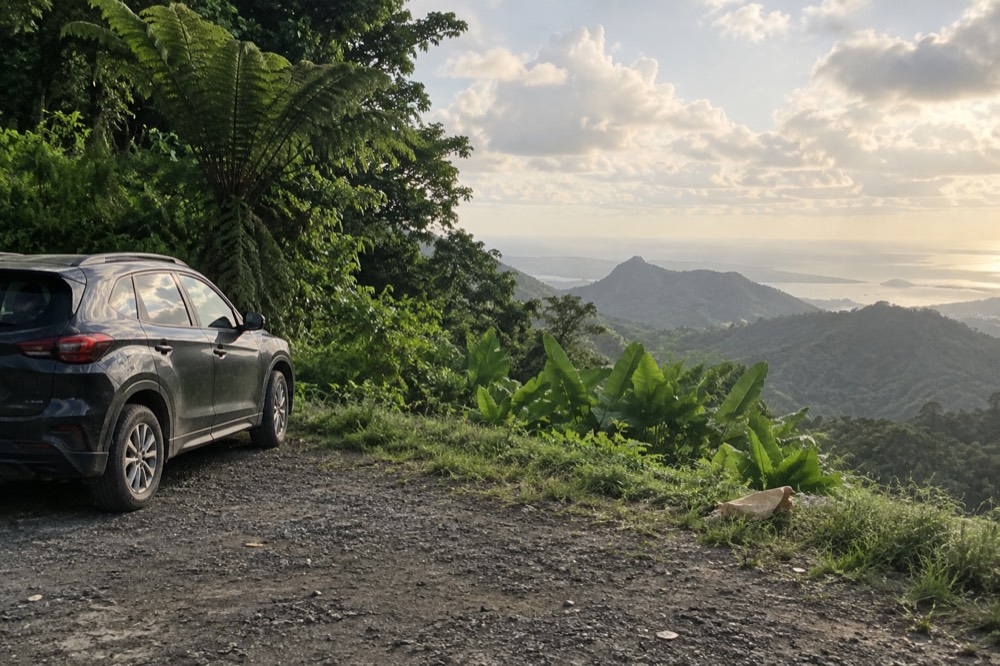 Empty parked car at a rainforest roadside pull-off surrounded by green forest